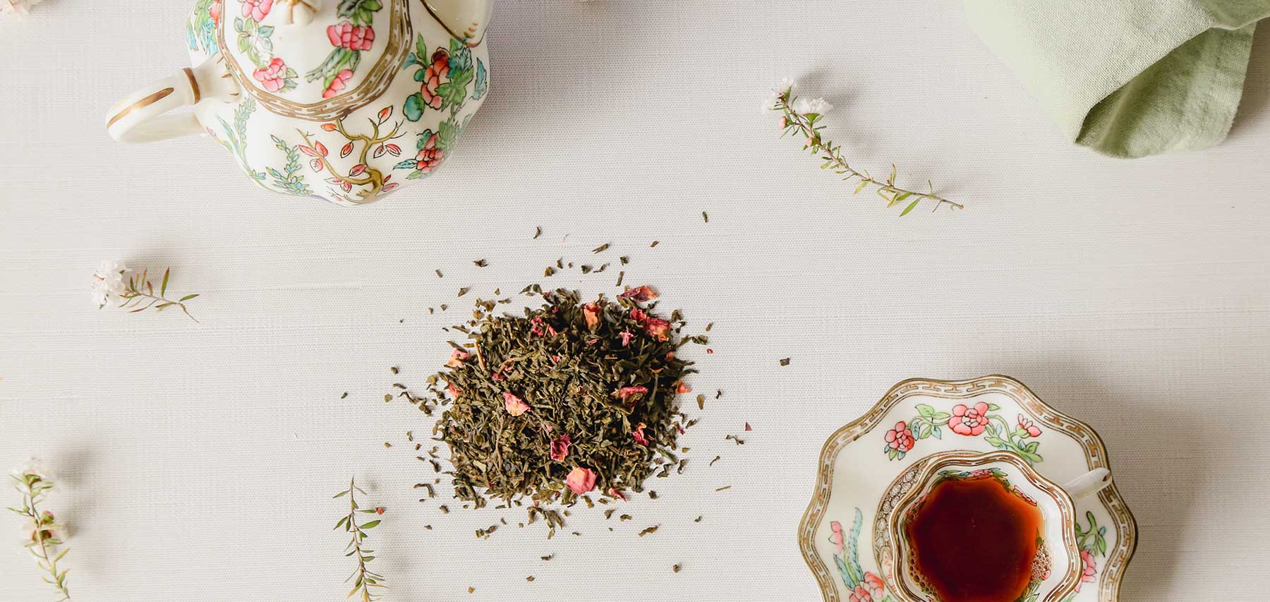 Green Tea with rose arranged on a table with vintage teapot and teacup with flowers