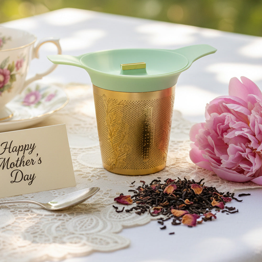 Tea infuser with dried tea leaves, pink flower, and 'Happy Mother's Day' card on a lace tablecloth.