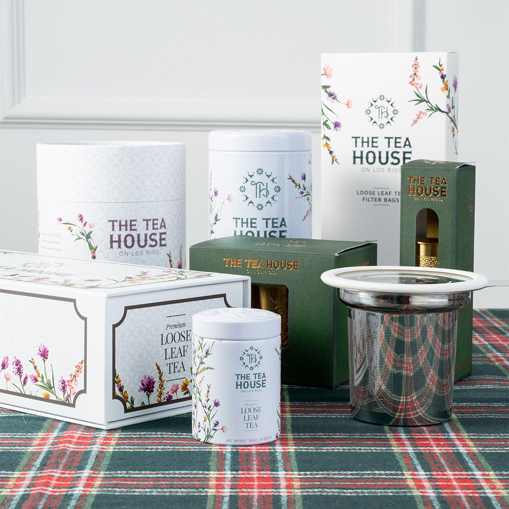 Collection of 'The Tea House' tea packaging and accessories on a plaid surface.