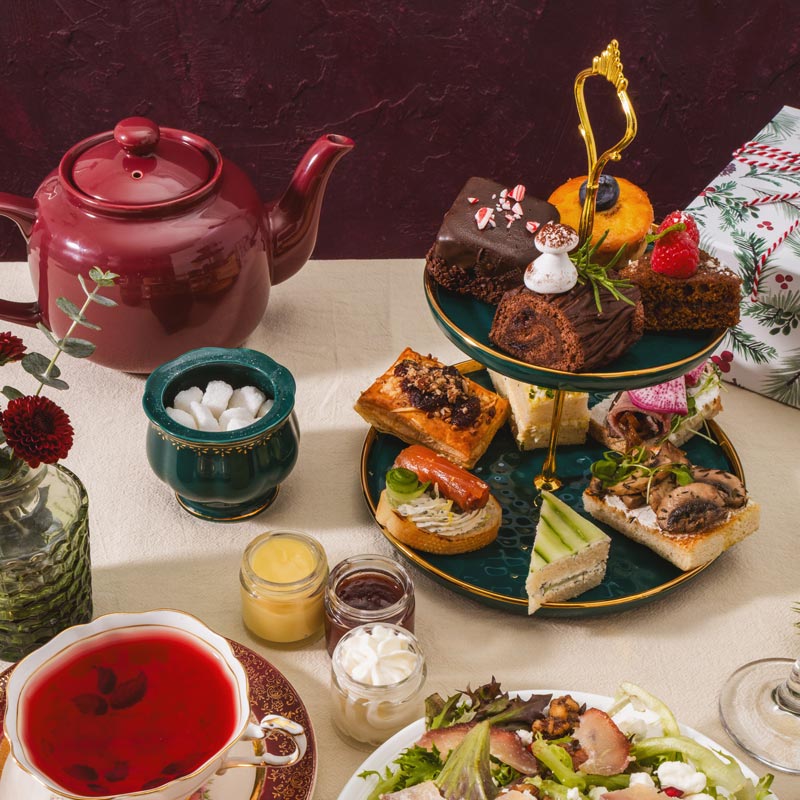 Tea set with a teapot, tea cup, and assorted finger foods on a table.