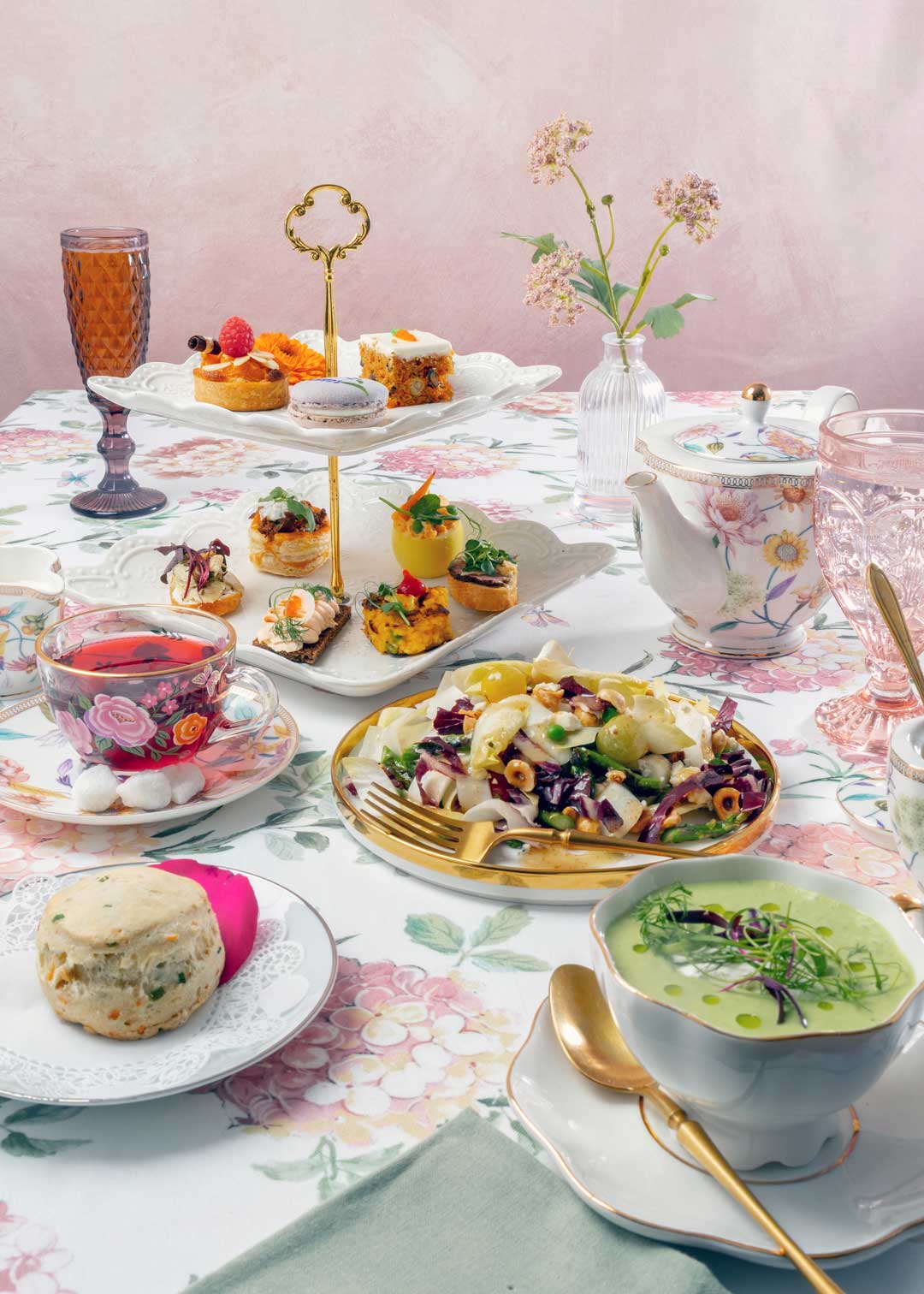 Spring Fling Tea Table setting with tea, pastries, and a salad on a floral tablecloth.