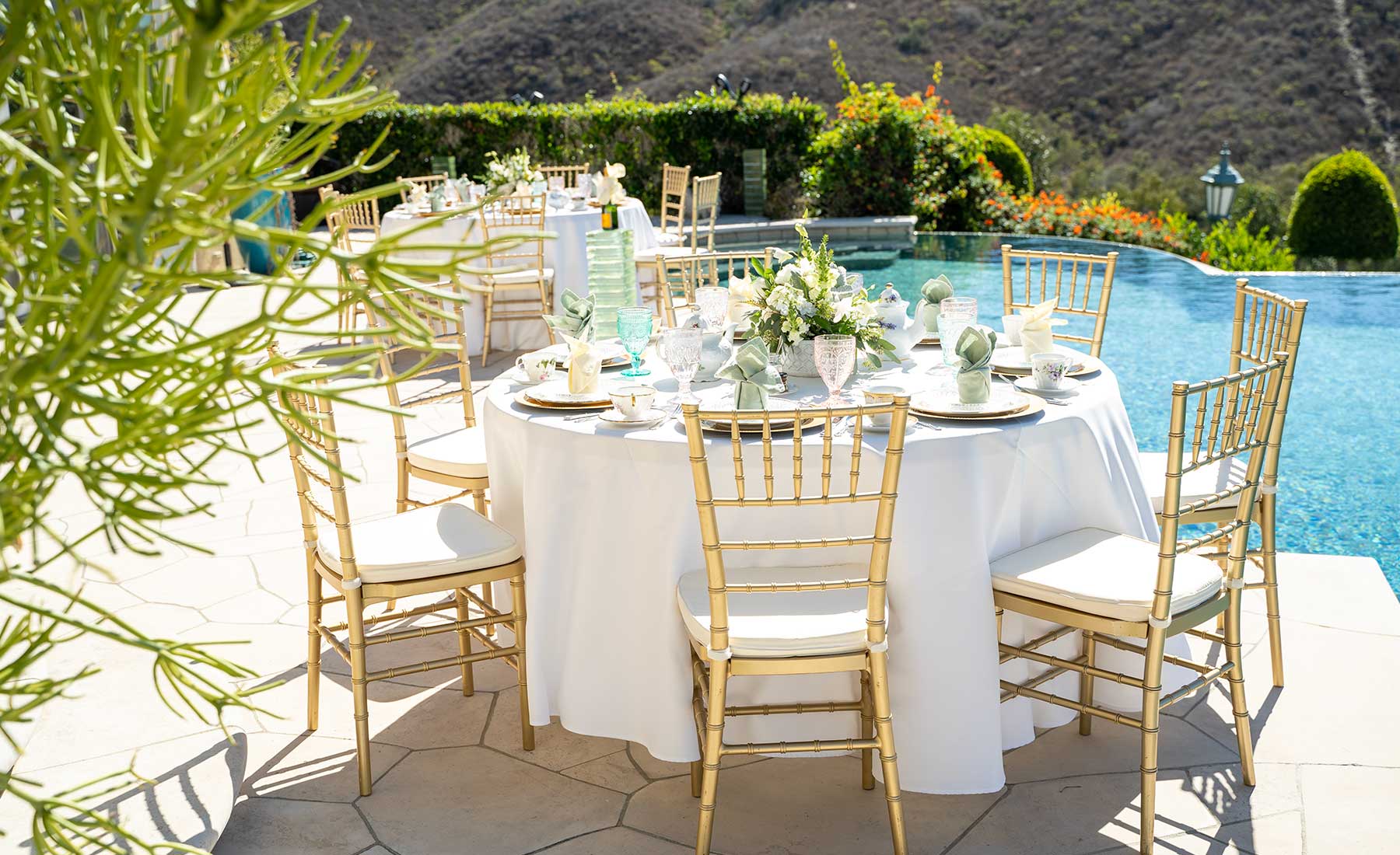 Poolside catering set up with chairs, tables, and china.