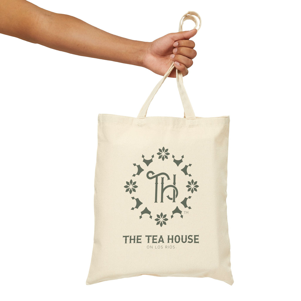 Canvas tote bag with 'The Tea House' logo held by a hand on a white background