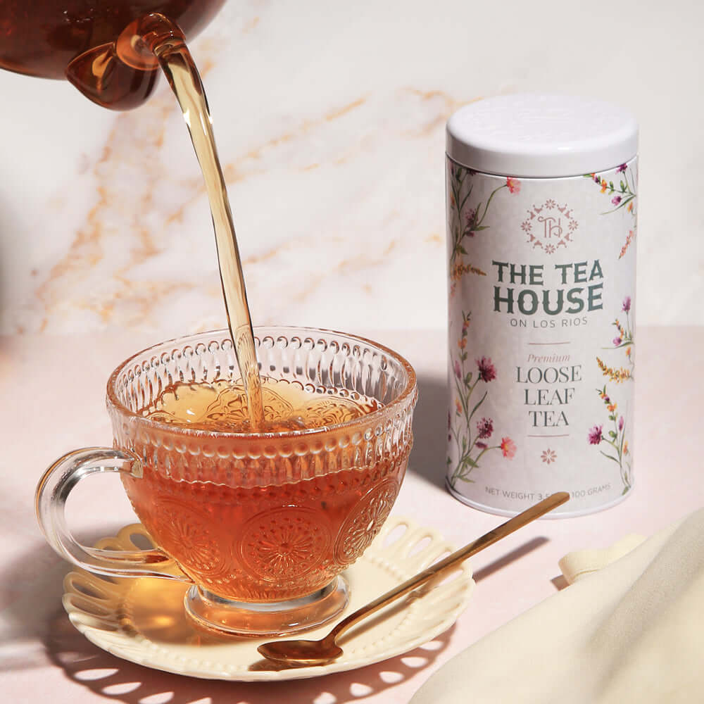 Formosa Oolong tea poured into a clear tea cup with a tin of loose tea behind