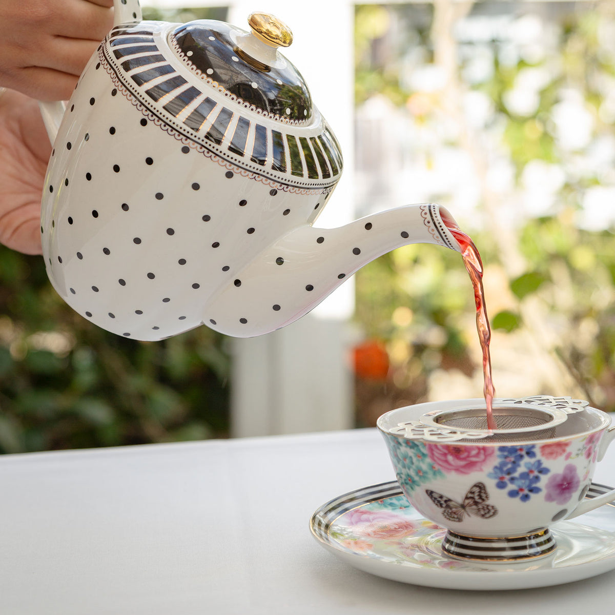 Peach Fruit Tea being poured from a black and white teapot through a empress strainer.