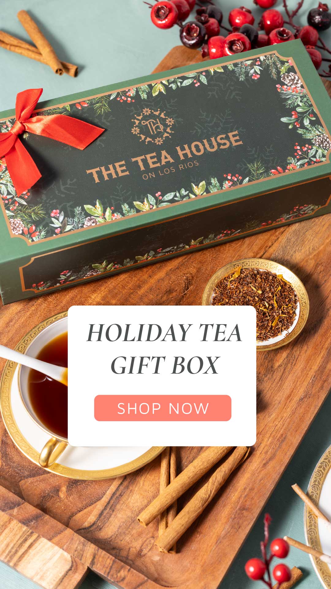 Tea gift box from The Tea House with a cup of tea, cinnamon sticks, and berries on a wooden board.