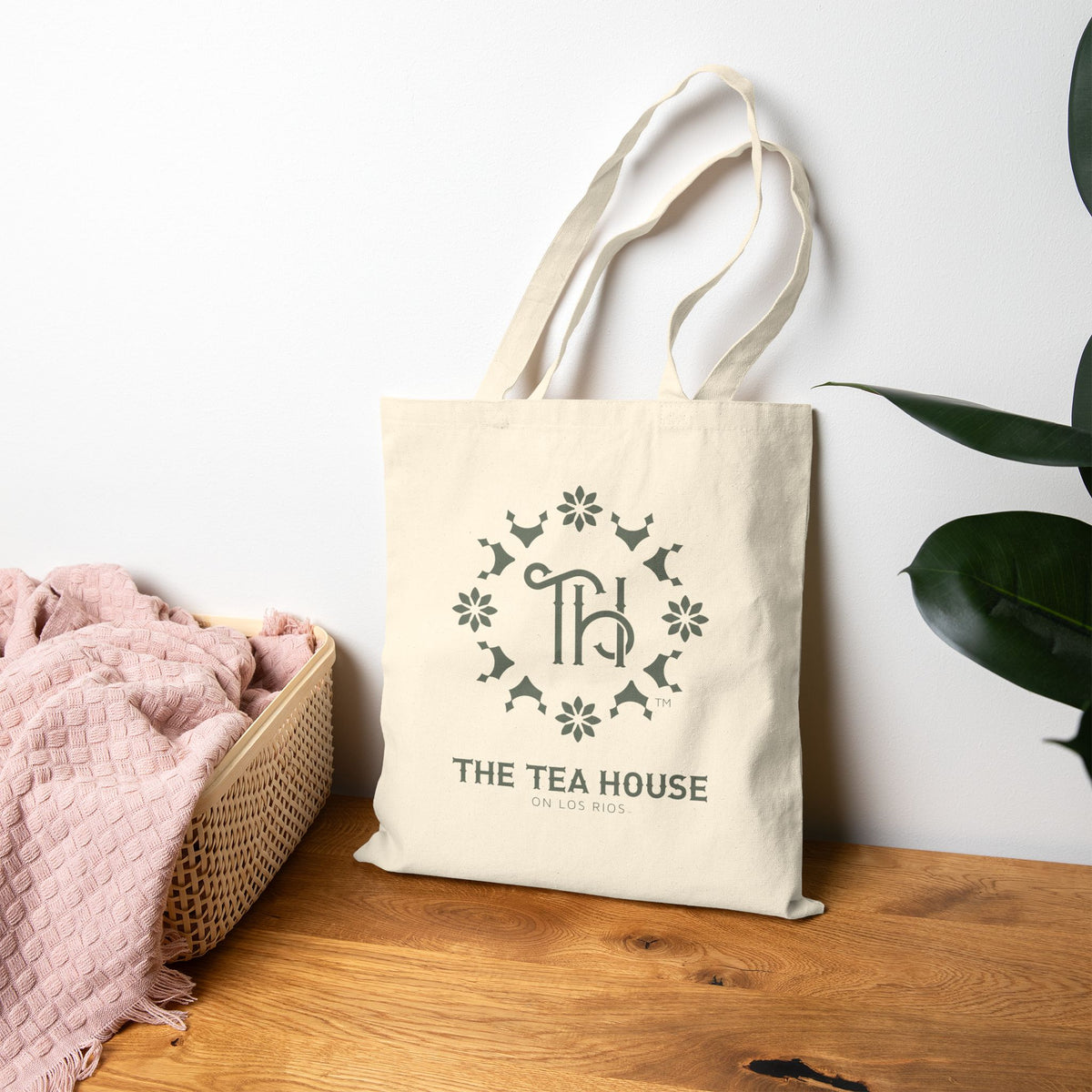 Canvas tote bag with 'The Tea House' logo on a wooden surface with a white background
