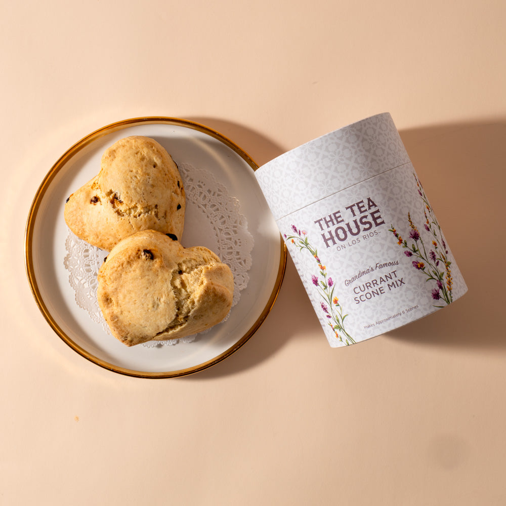 Two scones on a plate next to a container of The Tea House currant scone mix on a beige background