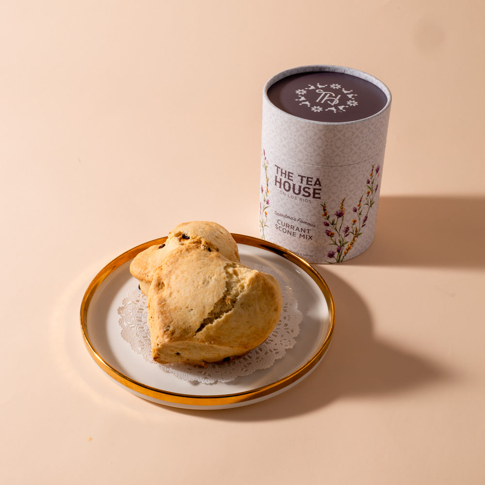 Scone on a plate with a scone mix container by 'The Tea House' on a beige background.
