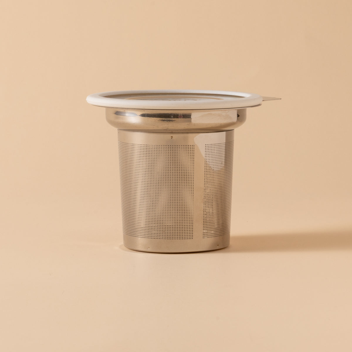 Metallic tea infuser on a beige background
