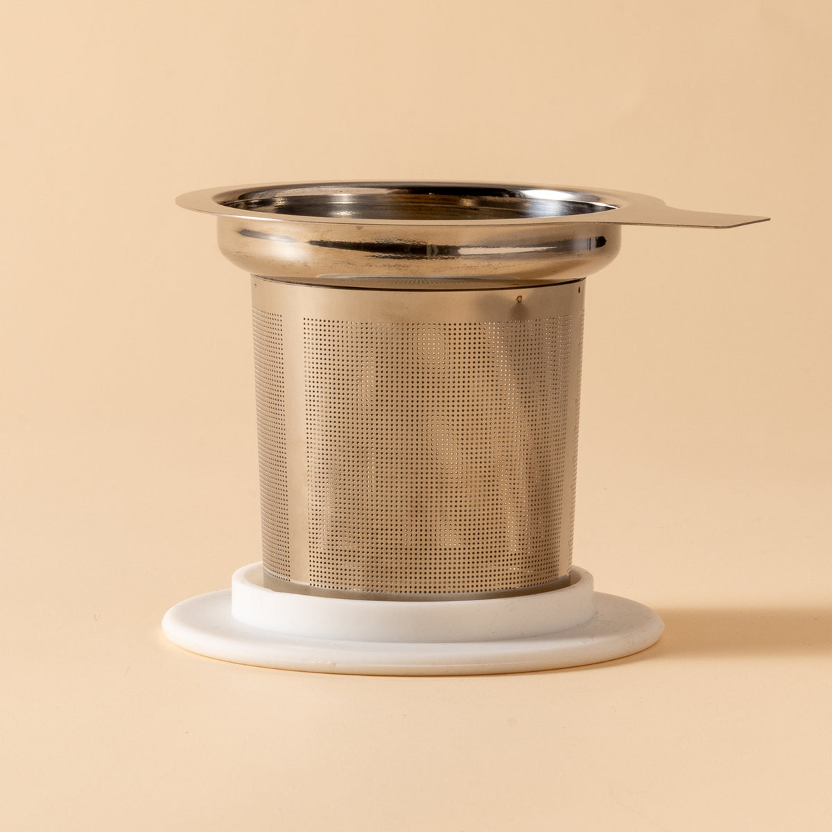 Metallic tea infuser on a beige background